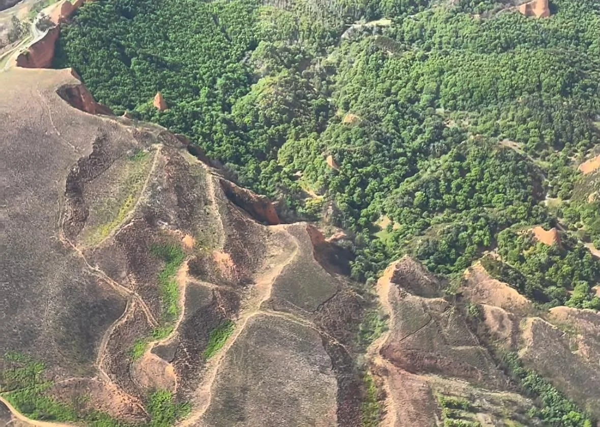 Vista aérea de la ladera quemada en Las Médulas junto al bosque que sobrevivió al incendio de Yeres