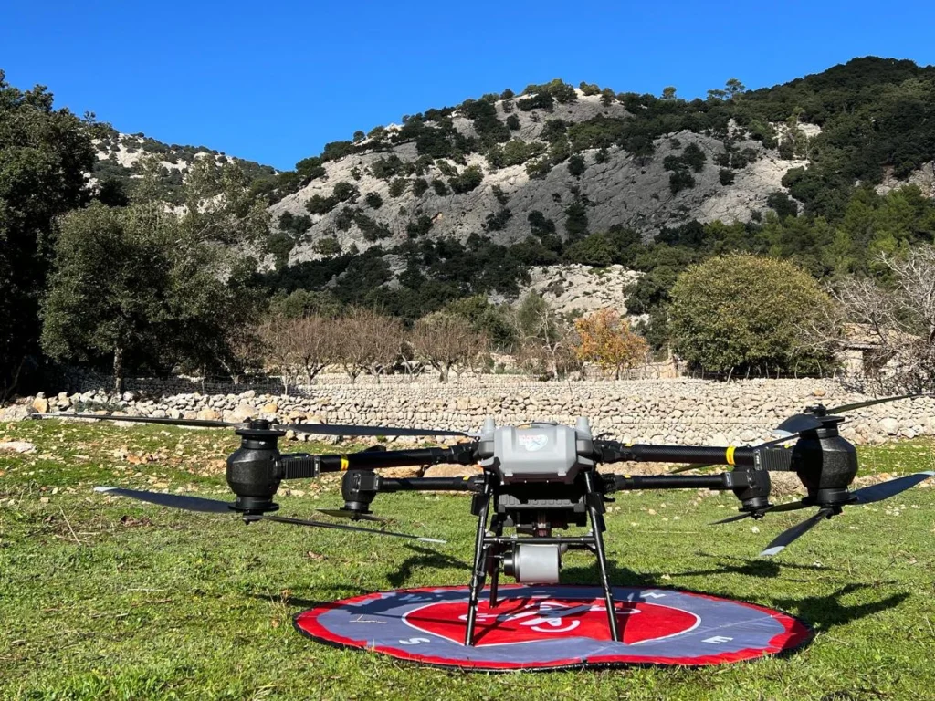 DJI FlyCart 30 en la base de despegue en la Sierra de Tramuntana, con bancales de piedra y la montaña al fondo